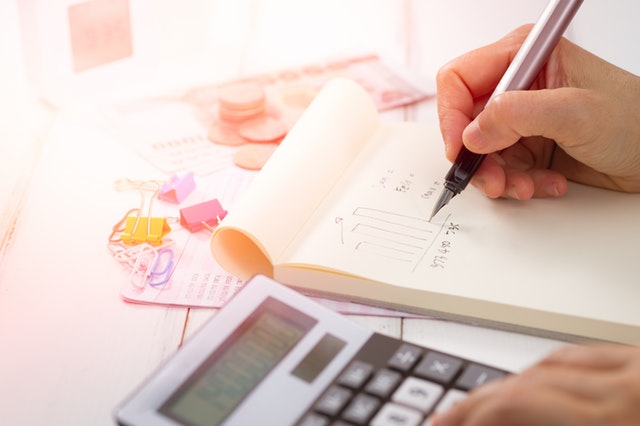 Close up of someone using a calculator and notebook to analyze the Midland real estate market